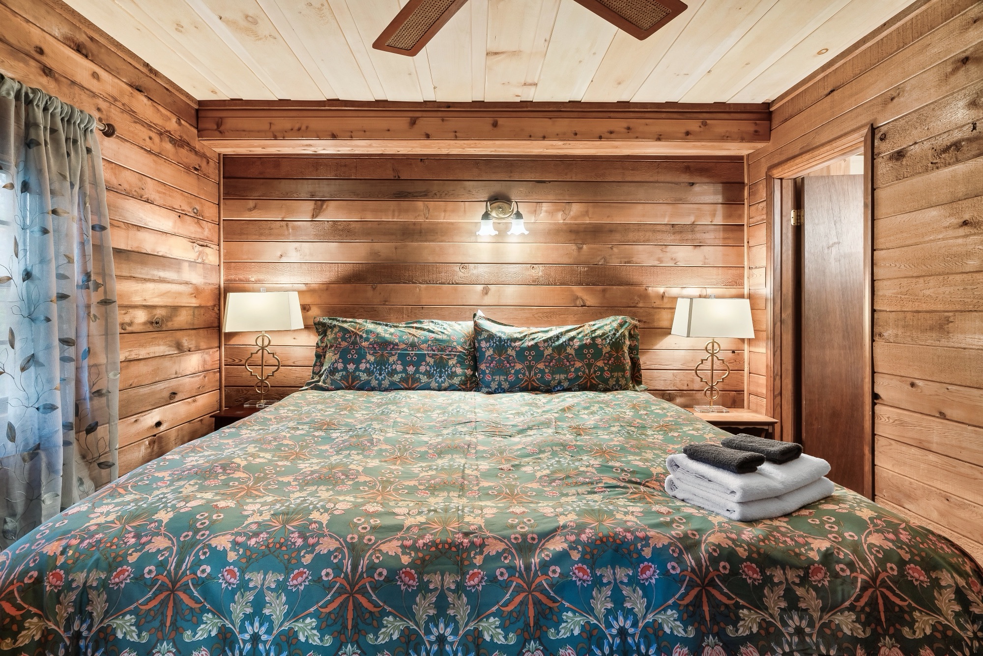 Primary bedroom at Rustic Retreat with a queen bed in teal floral bedding and matching bedside lamps